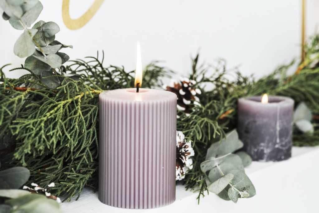 lit purple candle next to a holiday wreath