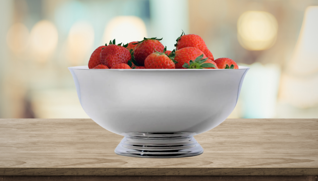 A beautiful silver Paul Revere Bowl filled full of delicious red strawberry's ripe for the eating