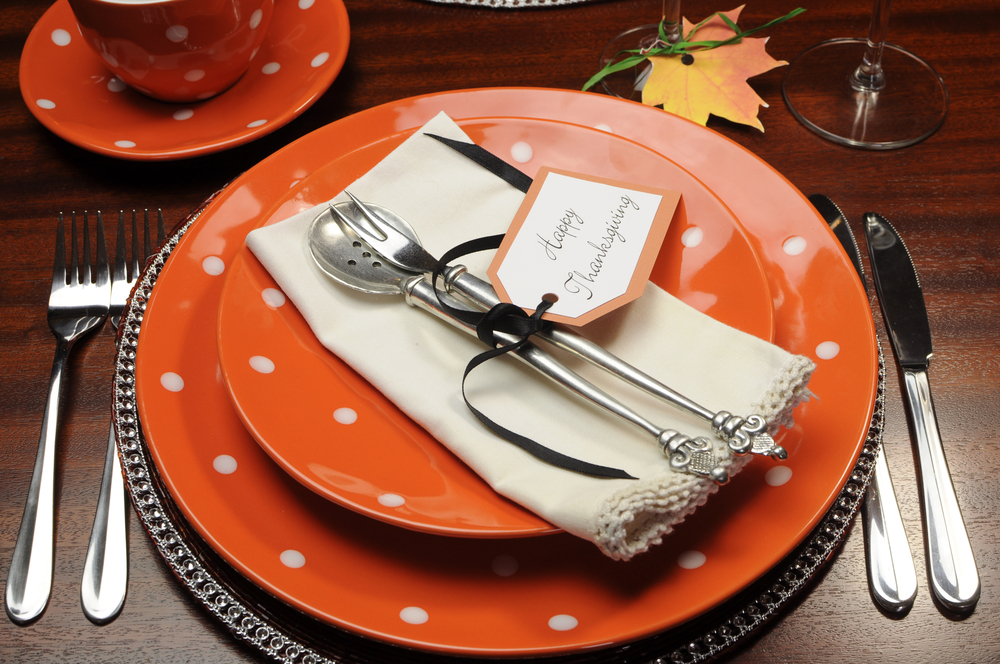 Thanksgiving place setting with silverware and festive plates.